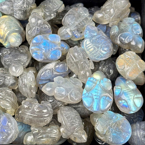 A collection of polished labradorite crystals carved into small, iridescent turtle shapes with blue flashes.