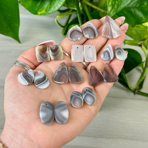 Botswana Agate cabochon pairs in various shapes and natural gray, white, and brown banded patterns.