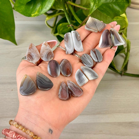 Botswana Agate cabochon pairs in various teardrop and oval shapes, with natural grey, white, and brown bands.