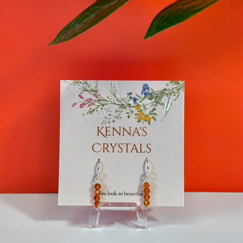 Big Carnelian earrings with orange beads and silver hooks, displayed on a floral "Kenna's Crystals" card.