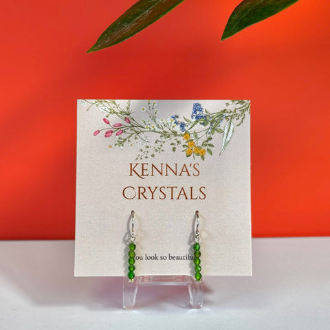 Chrome diopside earrings with small green beads on silver hooks, displayed on a floral "Kenna's Crystals" card.