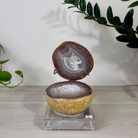 Druzy mermaid box with a brown agate geode exterior and sparkling white crystal center on a clear acrylic stand.