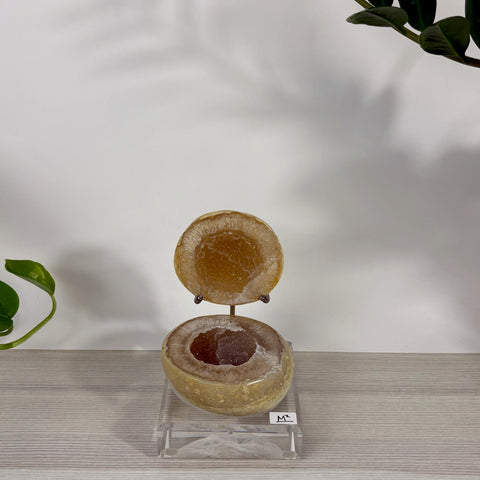 Open Druzy Mermaid Box geode with sparkling amber crystals on a clear acrylic stand, labeled M2.