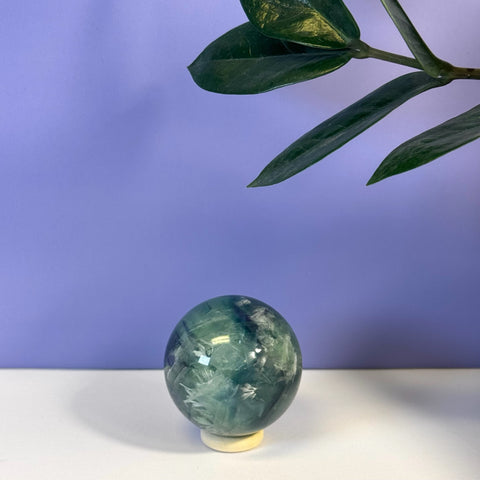 Feather Fluorite Sphere, a polished green, blue, and white crystal sphere on a light stand.