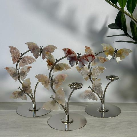 Flower agate butterfly flock with pink, cream, and brown wings on silver metal stands.