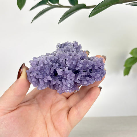 Hand holding a cluster of vibrant purple grape agate with a unique, bubbly botryoidal crystal texture.