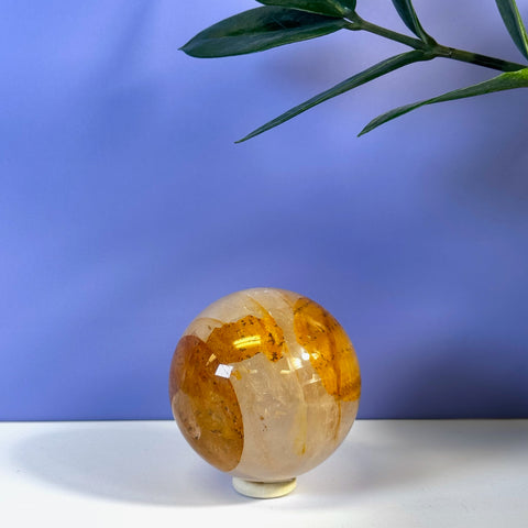 Girasol Golden Healer sphere with clear and warm amber-gold inclusions, on a white stand.