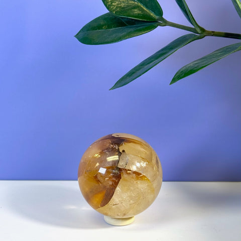 Girasol Golden Healer sphere, a polished yellow-orange crystal ball on a white stand.