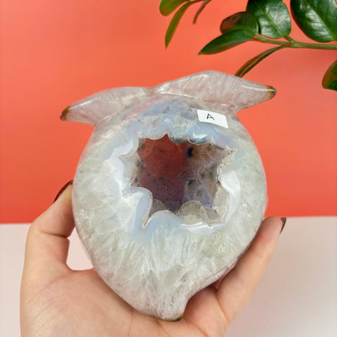 Handheld peach-shaped druzy agate carving with a sparkling crystalline hollow center and smooth translucent edges.