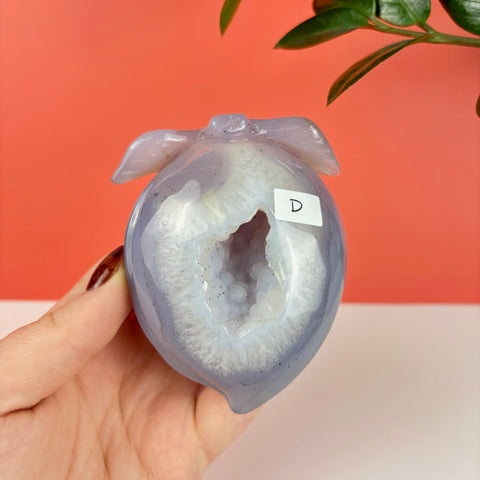 Hand-carved lavender agate peach featuring a sparkling druzy geode center held in a hand.