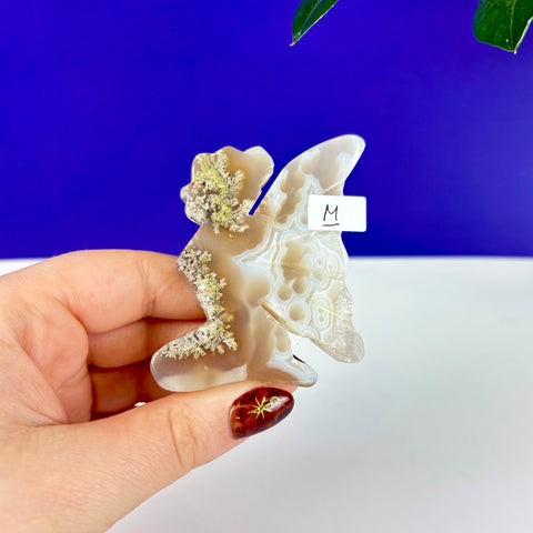 Kneeling fairy princess carving made of translucent scenic moss agate with intricate natural moss inclusions.