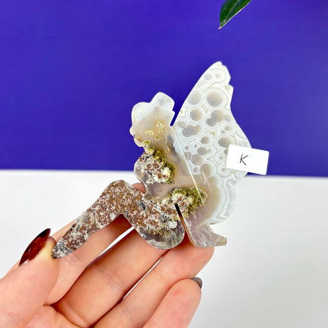 Hand-carved lounging fairy figurine made of scenic moss agate with intricate white patterns and earthy green inclusions.
