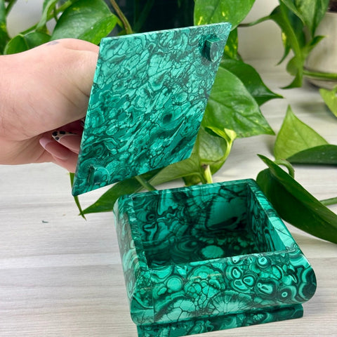 Handheld square malachite jewellery box with vibrant green swirling patterns and a hinged lid.
