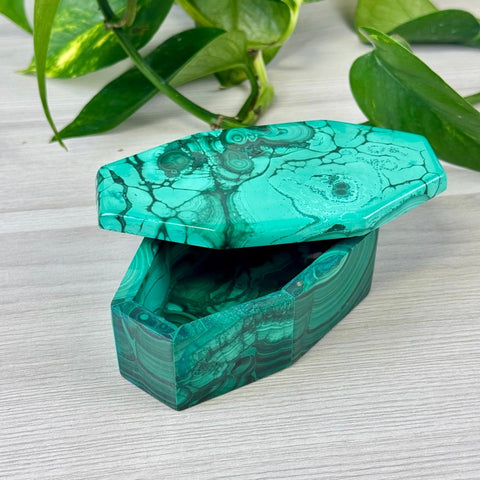 Coffin-shaped malachite jewellery box with vibrant green swirling patterns and a polished stone lid.