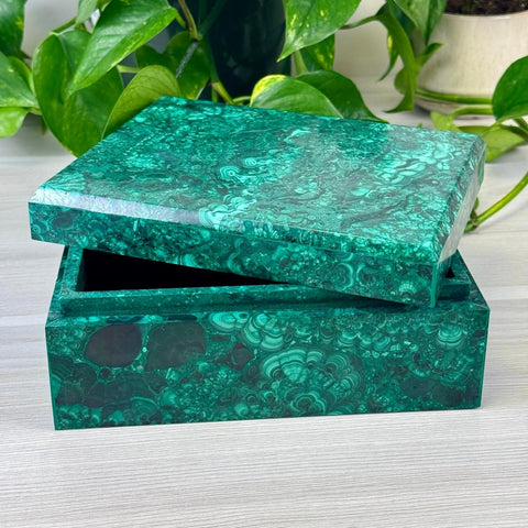 Rectangular malachite jewellery box with a vibrant green marbled pattern and a partially open lid on a wooden surface.