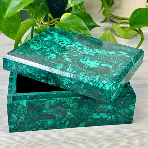 Rectangular malachite jewellery box with a polished green banded stone finish and a slightly open lid.