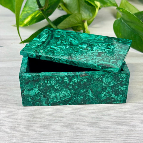 Rectangular malachite jewellery box with a vibrant green swirled pattern and a slightly open lid on a wooden surface.