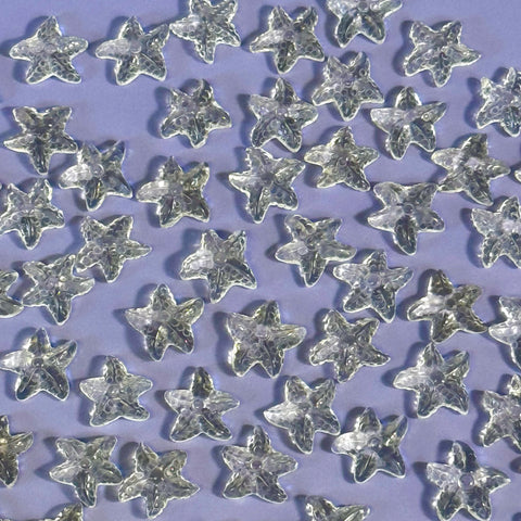Mini clear quartz sea star crystals scattered on a light purple surface.