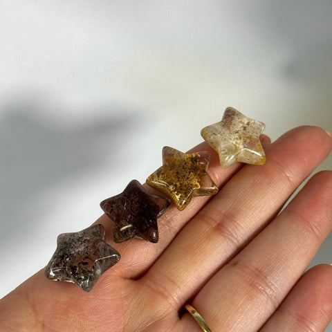 Four mini garden quartz stars, varying from dark to light brown, held in a hand.