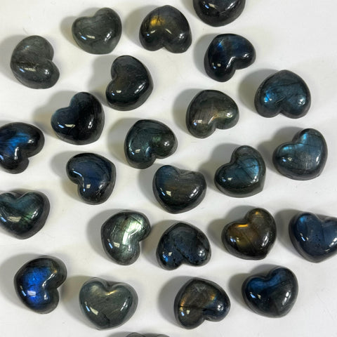 Polished mini labradorite heart crystals with iridescent blue and gold flashes on a white surface.