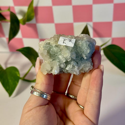 Mint-green fluorite with calcite specimen held in hand, showing crystalline texture.