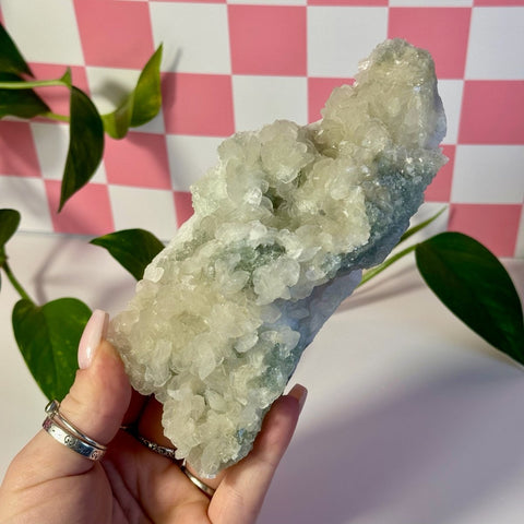 Mint-green fluorite with calcite specimen held in hand, showing crystalline texture.
