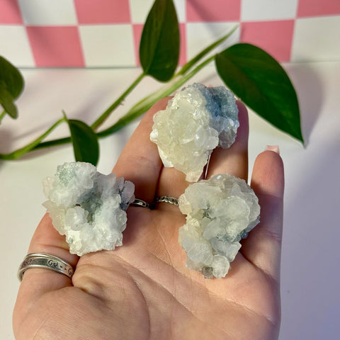 Three intuitively picked mint-green fluorite with calcite specimens held in a hand.