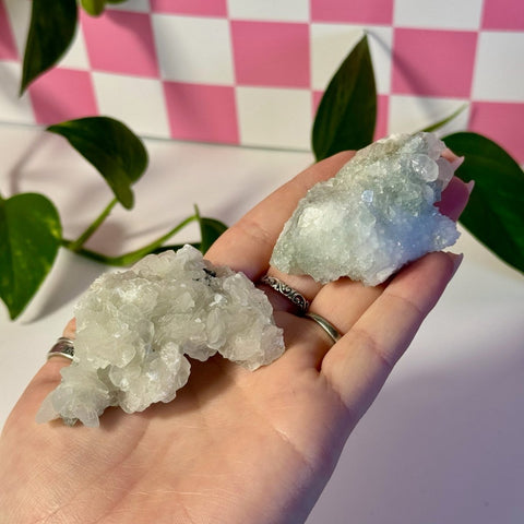 Mint-green fluorite with calcite specimen held in a hand, showing two raw crystal clusters.