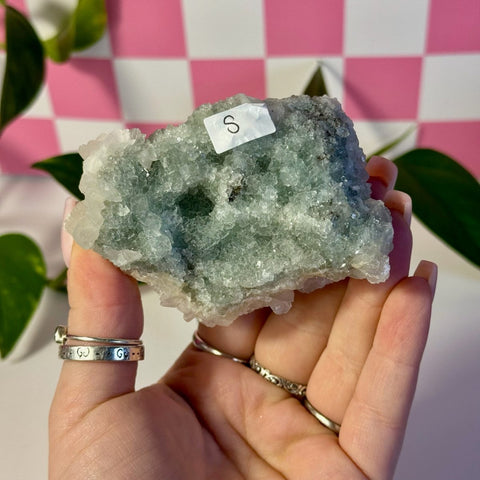 Mint-green fluorite with calcite specimen, held in a hand, showing its rough texture and natural form.