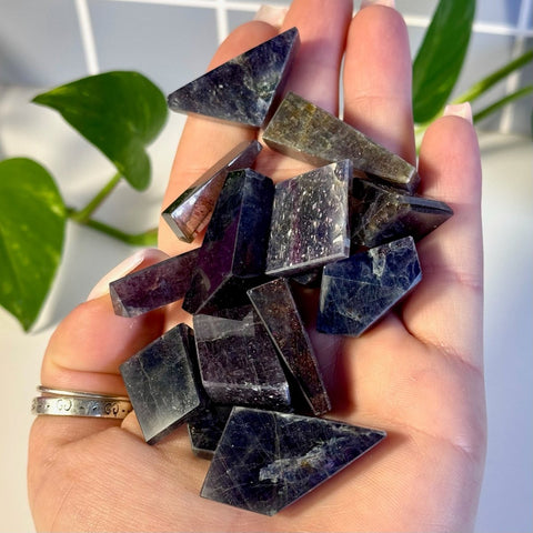 Handful of deep purple and indigo Mystery Galaxy Iolite crystal shards with natural inclusions and polished surfaces.