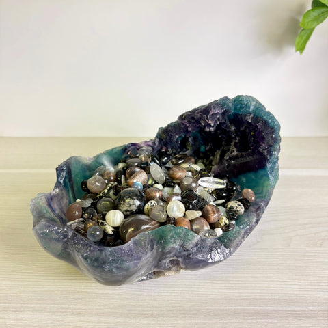 Large purple and green fluorite crystal bowl filled with a variety of polished gemstone tumbles and crystals.