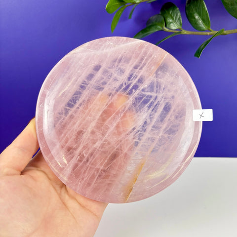 Handheld circular rose quartz plate with natural translucent pink veining and a polished finish.