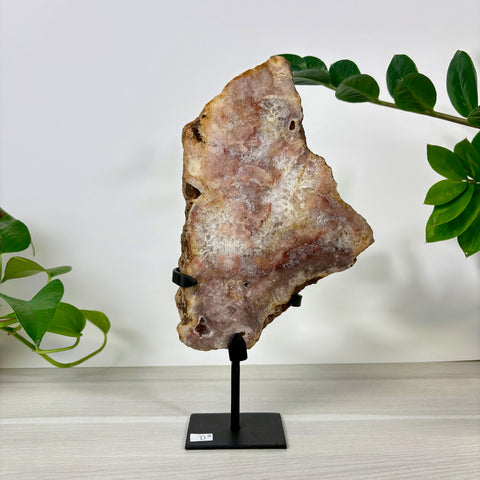 Large pink amethyst crystal slab with white druzy quartz center, displayed on a black metal stand.