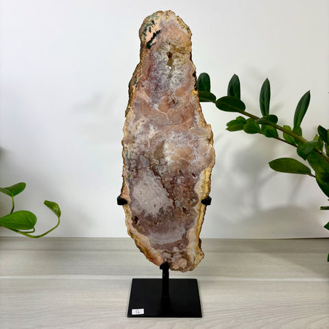 Tall pink amethyst crystal slab with sparkling druzy center, displayed on a black metal stand.