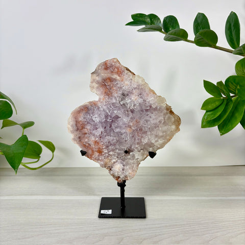 Large pink amethyst crystal slab with sparkling purple clusters on a black metal display stand.