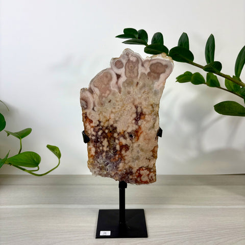 Pink amethyst slab with marbled white and reddish-brown patterns on a black metal display stand.
