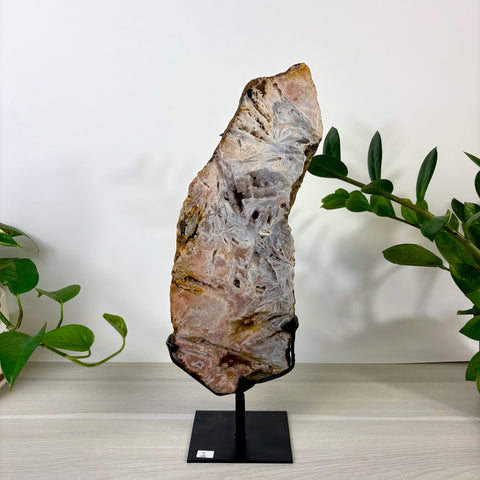 Tall pink amethyst slab with intricate white crystalline patterns on a black metal display stand.