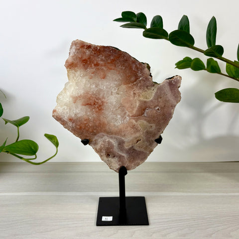 Large pink amethyst crystal slab with crystalline texture on a black metal display stand.