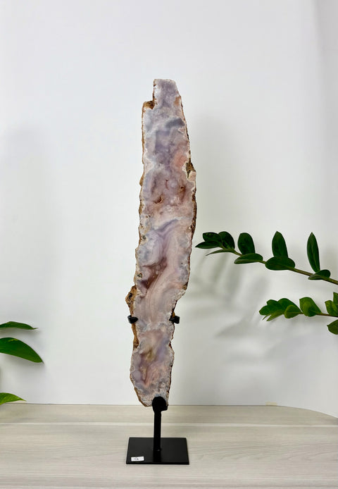 Tall, slender pink amethyst crystal slab with swirling lavender and white patterns, displayed on a black metal stand.