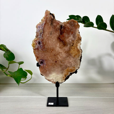 Large pink amethyst crystal slab with natural crystalline texture on a black metal display stand.
