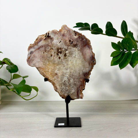 Large pink amethyst geode slice with sparkling quartz crystals on a black metal display stand.