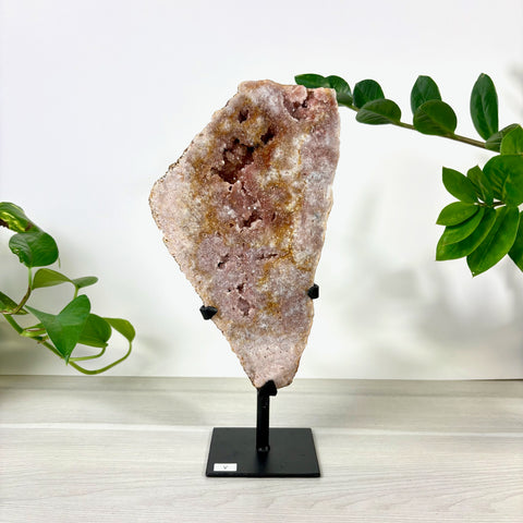 Large pink amethyst geode slice with sparkling crystals on a black metal display stand.