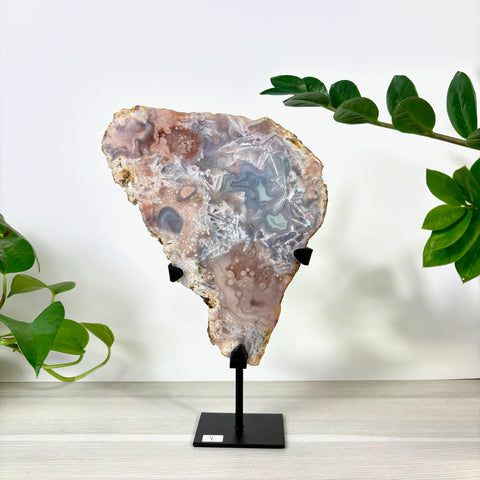 Large pink amethyst slab with intricate crystalline patterns and agate banding on a black metal display stand.