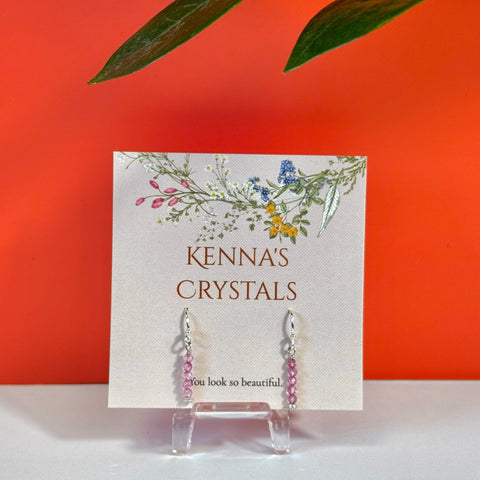 Dangling pink topaz earrings with silver hooks on a "Kenna's Crystals" card.