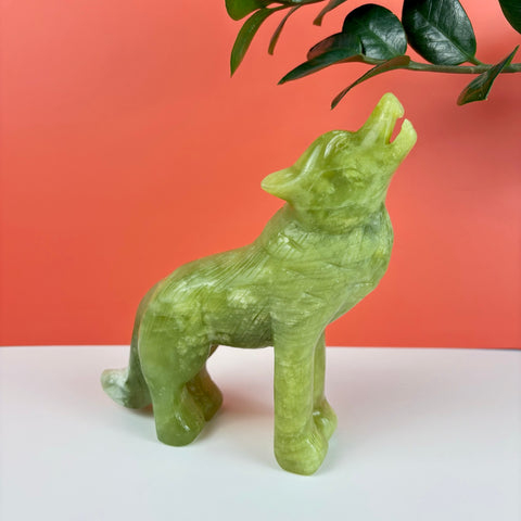 Hand-carved light green serpentine stone wolf figurine howling, featuring smooth polished textures and natural veining.