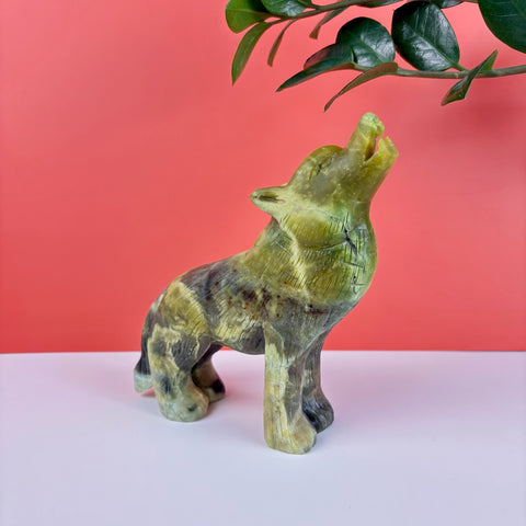 Hand-carved green serpentine stone wolf figurine howling, featuring natural mineral marbling and polished texture.