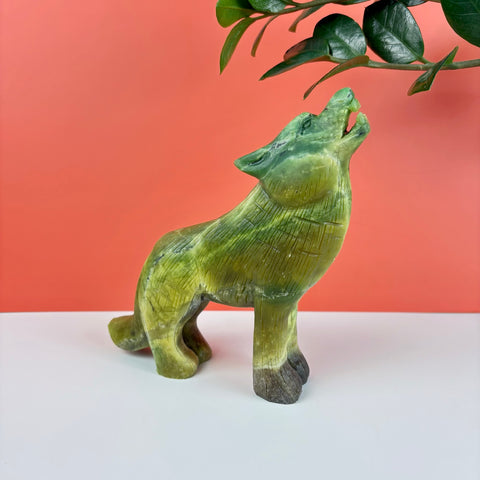 Hand-carved green serpentine stone wolf figurine howling, featuring detailed fur textures and polished finish.