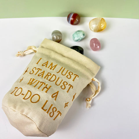 Natural cotton canvas drawstring pouch with gold embroidery and assorted tumbled crystals.