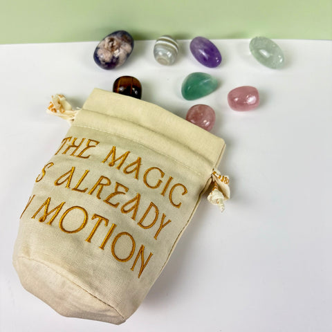 Natural canvas drawstring pouch with gold embroidery and polished crystals.