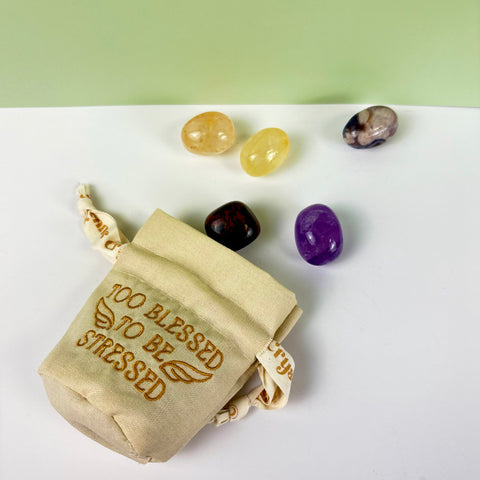 Small beige cotton-linen drawstring pouch with gold embroidery and five assorted polished crystals.